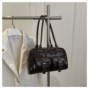 Detailed view of dark brown glossy leather underarm bag with silver metal buckles