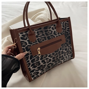Dettaglio della borsa leopardata con manici in pelle marrone e tasca frontale con zip