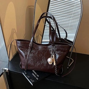 Brown faux leather tote bag with vintage texture and baseball glove charm accessory