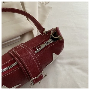 Detail von rotem Litschi-Leder mit weißem Stern-Patch und silbernen Metallteilen