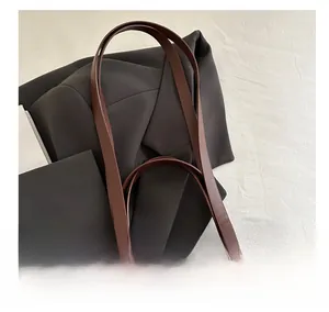Detail of dark brown leather tote handle with contrast white stitching and wide strap design