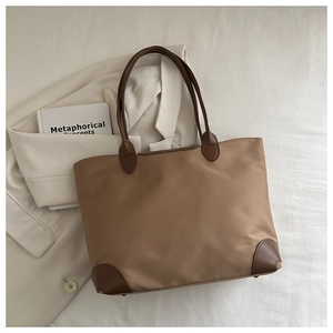 Dettaglio di una grande borsa tote in nylon kaki con manici in pelle marrone e base rinforzata