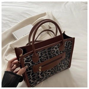Dettaglio della borsa leopardata con manici in pelle marrone e cerniera dorata