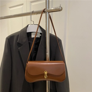 Chic brown leather baguette shoulder bag with gold metal twist lock on a display rack