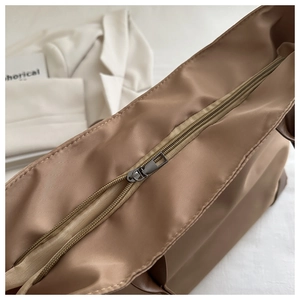 Dettaglio borsa tote in nylon kaki con cerniera in metallo liscia e cuciture di precisione