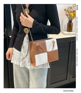 Détail de la couture à carreaux marron et blanc sur un sac structuré avec chaîne
