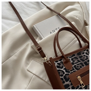 Dettaglio borsa leopardata con finiture in pelle marrone e tasca con zip