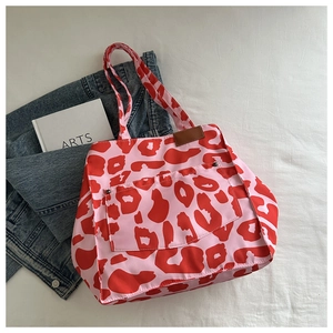Detailed view of red leopard print tote bag with front rivet pocket and leather tag