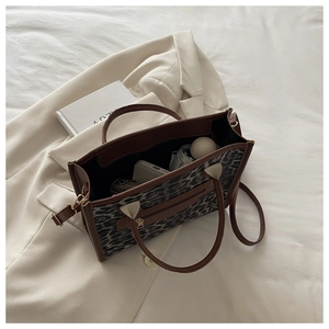 Dettaglio borsa tote leopardata capiente con manici in pelle marrone su sfondo bianco