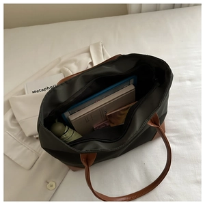 Vista interna della grande borsa tote con libri e ombrello su biancheria da letto bianca