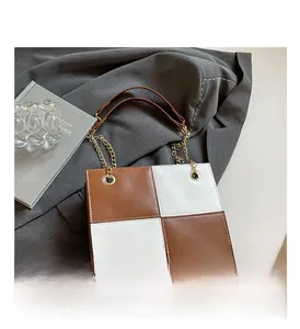 Détail du sac à bandoulière carré à carreaux marron et blanc avec bandoulière chaîne dorée