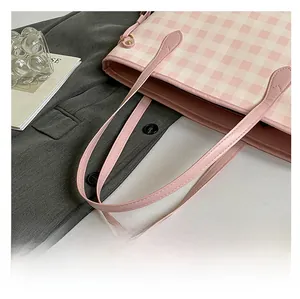 Dettaglio del manico della borsa a scacchi rosa e bianchi posata su un blazer elegante