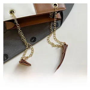Détail de la bandoulière chaîne et de l'épaulette en cuir sur le sac bicolore chic