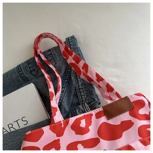 Close-up of animal print tote bag fabric with pink base and brown leather logo tag