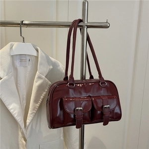 Chic burgundy patent leather shoulder bag with decorative front pockets and strap