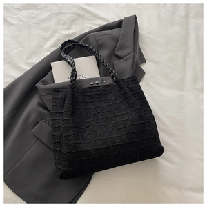 Détail du cabas noir avec tissu texturé quadrillé et poignée en cuir tressé élégante