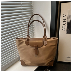 Dettaglio di una borsa tote in nylon marrone con manici in pelle e chiusura a patta