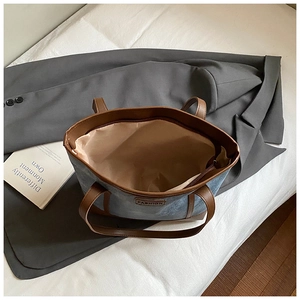 Detailed interior view of a large denim tote bag showing brown leather zipper closure