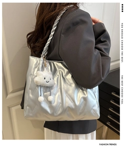 Detailed shot of silver quilted tote bag with a white plush cloud smile charm
