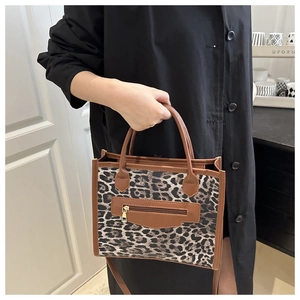 Dettaglio della borsa leopardata con finiture in pelle marrone e zip frontale decorativa