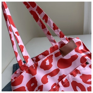 Detail of pink leopard print tote bag featuring brown leather patch and metallic rivets