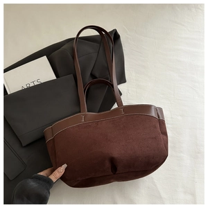 Detail of dark brown suede tote bag featuring leather handles and contrast white stitching