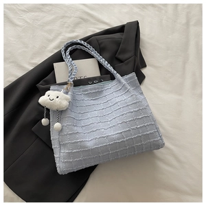 Détail du sac cabas bleu clair texturé gaufré avec anses tissées et breloque nuage