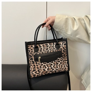 Dettaglio borsa shopper leopardata con bordi in pelle nera e cerniera metallica dorata