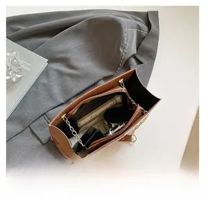 Intérieur spacieux du sac en cuir marron avec chaîne dorée et pochette zippée incluse