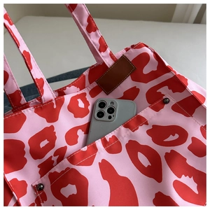 Detail of pink leopard tote bag with deep front pocket and brown leather label