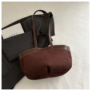 Close-up of deep brown tote bag with white contrast stitching and soft suede texture