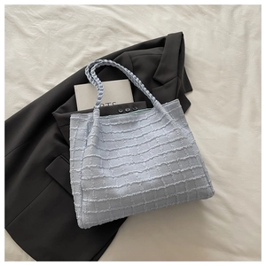 Détail du sac cabas à carreaux bleu clair avec franges et poignée tissée élégante