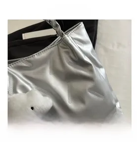Close-up of silver tote bag featuring pleated texture and a cute cloud plush charm