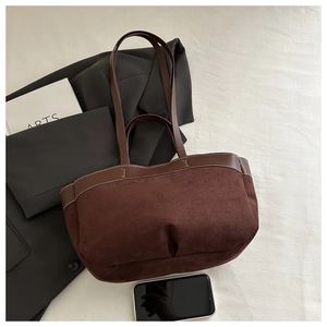 Detail of dark brown suede tote bag featuring white contrast stitching and smooth leather handles