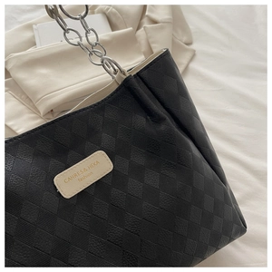 Close-up of black checkered tote bag with metallic chain strap and logo patch detail