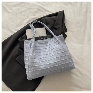 Détail du sac cabas bleu clair tissé montrant la texture sur une veste noire
