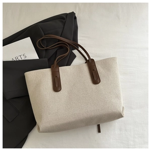 Flat lay of canvas tote bag with brown leather handles on textured background