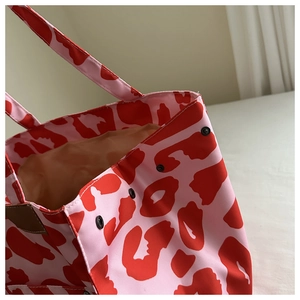Macro detail of leopard print nylon tote showing side metal snaps and textured fabric