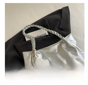 Detail of silver metallic handbag with woven handle and a white plush cloud charm accessory