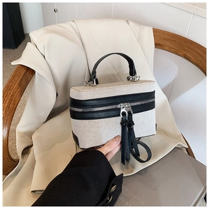 Detail of contrast stitch canvas box bag with black leather trim and double zippers