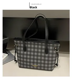 Dettaglio della borsa tote a quadri neri con tracolla in pelle e logo dorato
