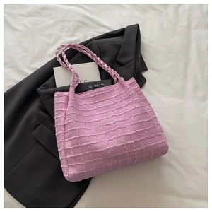 Détail d'un sac cabas rose clair gaufré avec poignées tressées et tissu texturé