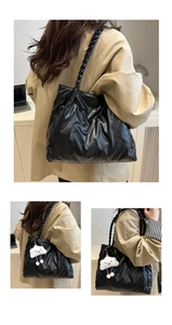 Detail of black quilted tote bag with chunky braided strap and white plush cloud charm