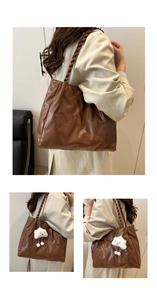 Detail of brown leather tote bag with braided handles and cloud plush charm decoration
