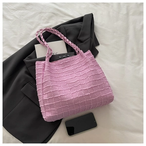 Détail du cabas rose à texture gaufrée avec anses tressées sur un décor de literie blanc chic