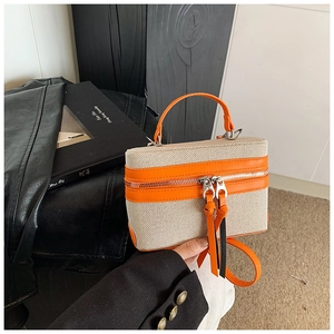 Detail of color-block box bag with orange leather handles and silver dual zippers