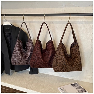 Three leopard print tote bags in vintage hobo styles hanging in a minimalist setting