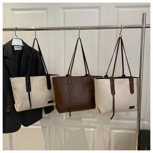 Detailed comparison of minimalist tote bags in canvas and leather hanging on a metal rack