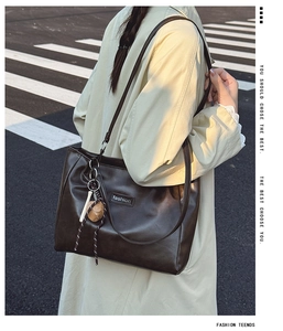 Close-up of dark brown tote bag with decorative dice charm and fashion logo detail