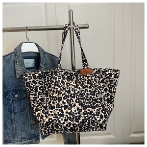 Close-up of leopard print canvas tote bag with front pocket hanging on a metal hanger